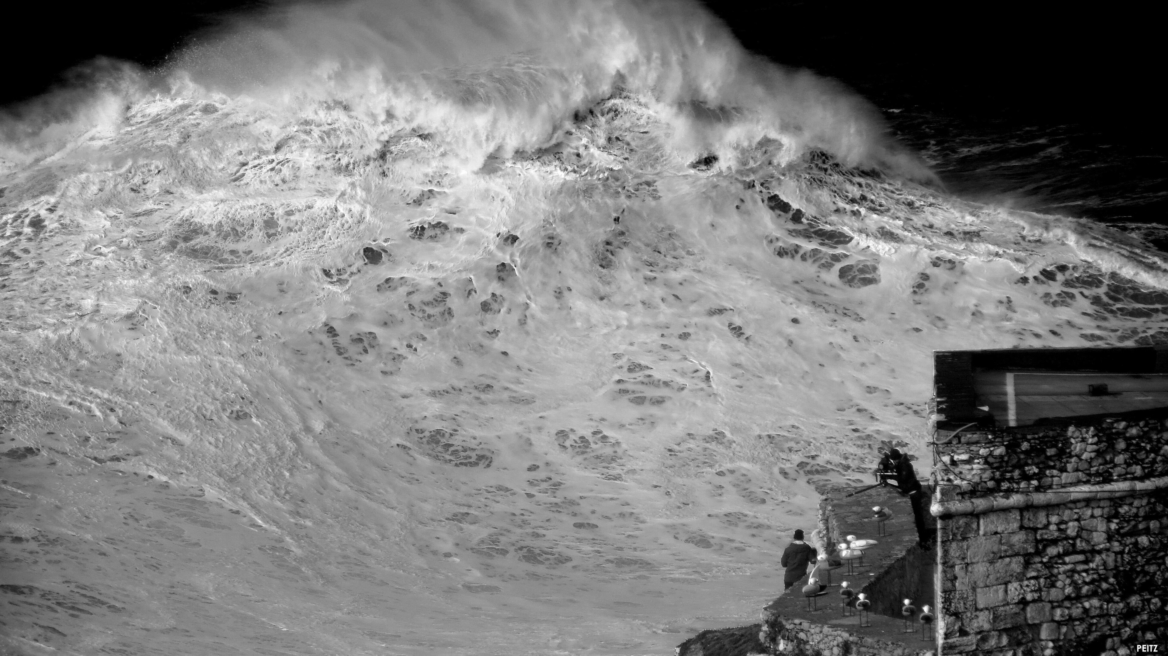 A surfer descending the face of a big wave at Nazaré